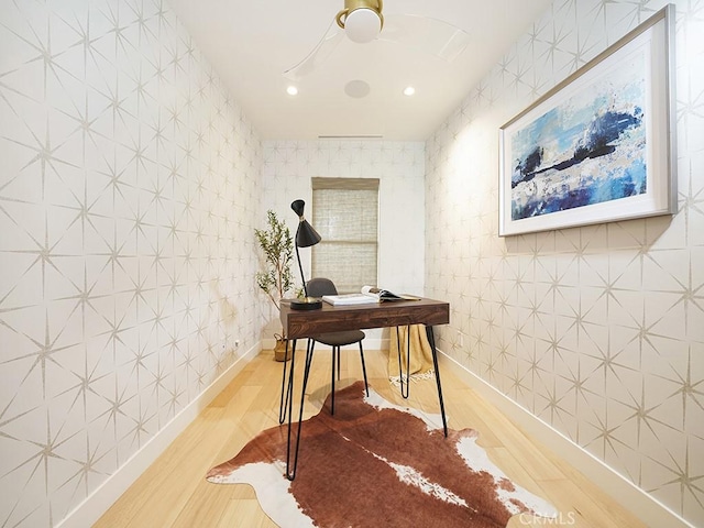 office area featuring hardwood / wood-style floors, ceiling fan, and tile walls