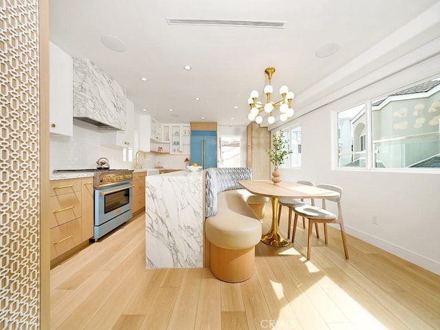 kitchen with sink, light hardwood / wood-style flooring, white cabinetry, high end appliances, and light stone countertops