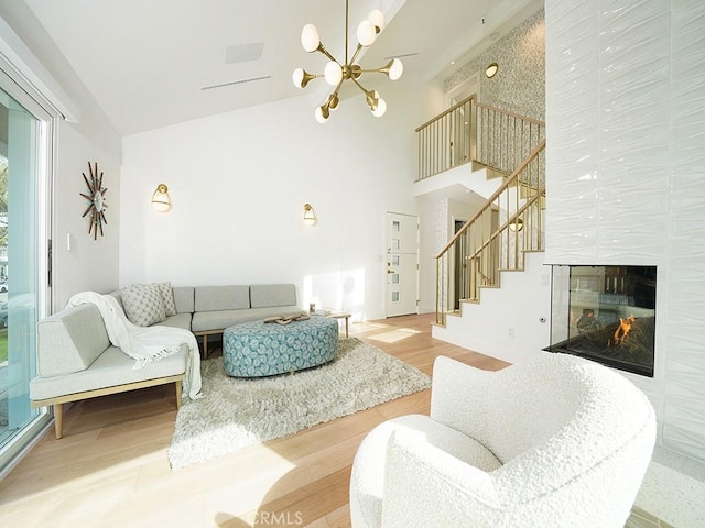 living room with a multi sided fireplace, high vaulted ceiling, a chandelier, and light wood-type flooring