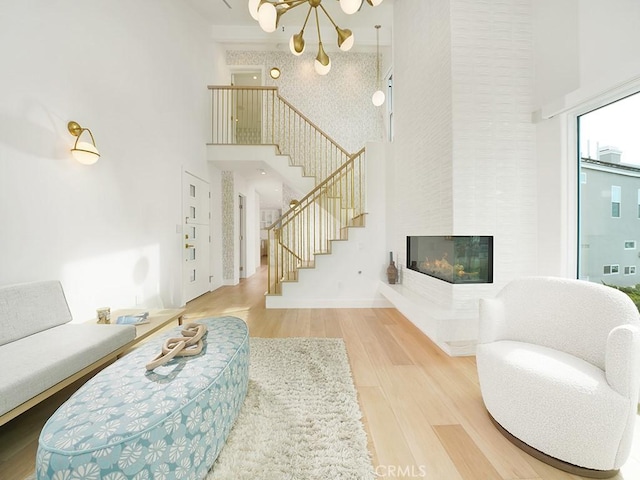 living room featuring hardwood / wood-style flooring, a towering ceiling, a fireplace, and a chandelier