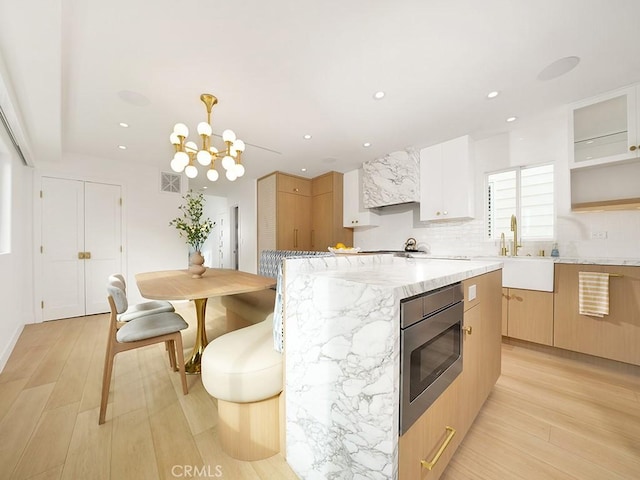 kitchen featuring sink, white cabinetry, a center island, stainless steel microwave, and pendant lighting