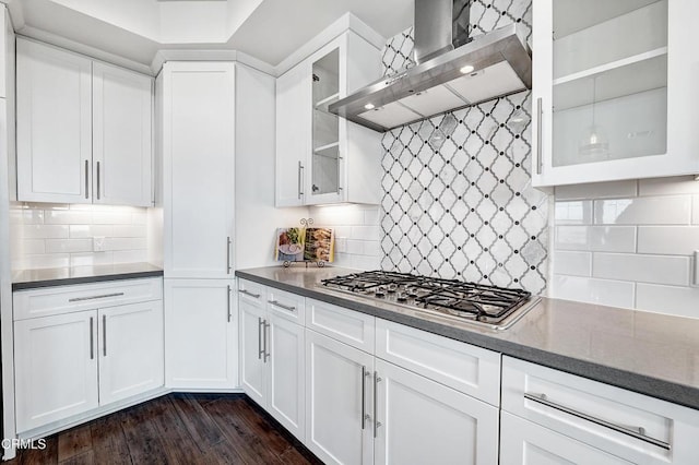 kitchen featuring dark hardwood / wood-style floors, tasteful backsplash, white cabinets, stainless steel gas cooktop, and wall chimney exhaust hood