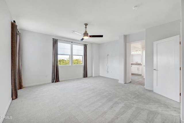 unfurnished bedroom with connected bathroom, sink, light colored carpet, and ceiling fan