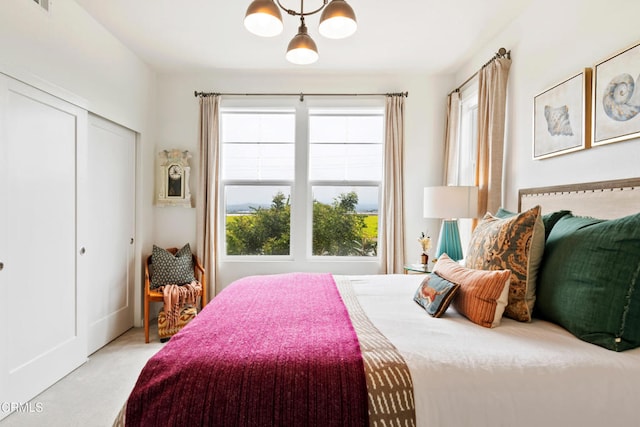 carpeted bedroom with a notable chandelier and a closet