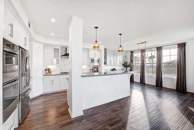 kitchen featuring pendant lighting, white cabinetry, decorative backsplash, stainless steel appliances, and dark wood-type flooring