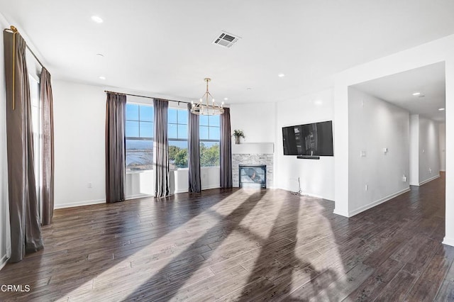 unfurnished living room featuring a fireplace, dark hardwood / wood-style flooring, and a chandelier