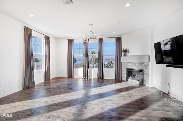 living room featuring hardwood / wood-style flooring, a stone fireplace, and a notable chandelier