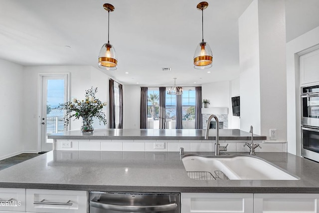 kitchen featuring white cabinetry, stainless steel appliances, decorative light fixtures, and sink