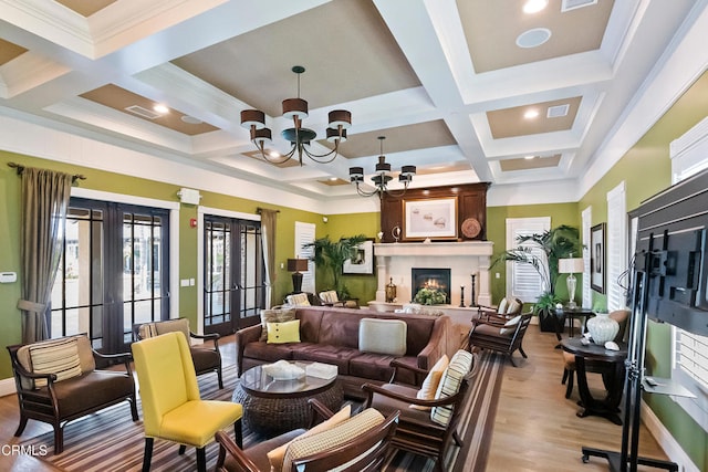 living room featuring a fireplace, french doors, a chandelier, beam ceiling, and light hardwood / wood-style flooring