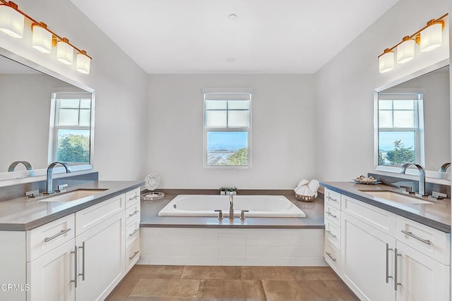 bathroom with a relaxing tiled tub, vanity, and tile patterned flooring