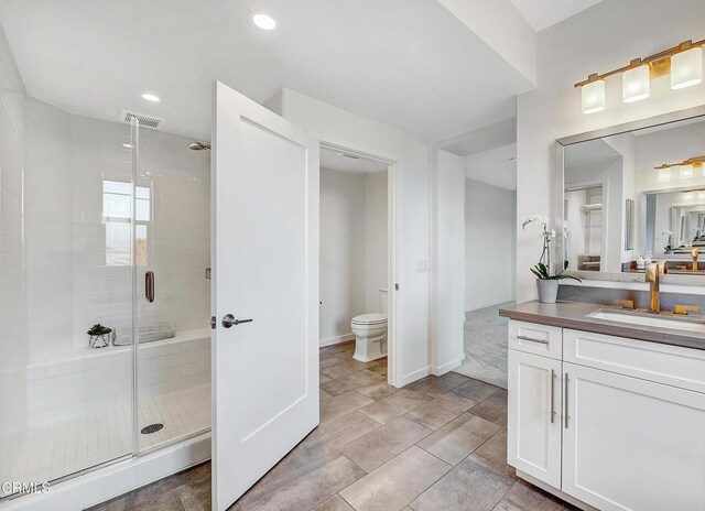 bathroom with vanity, toilet, and a shower with shower door