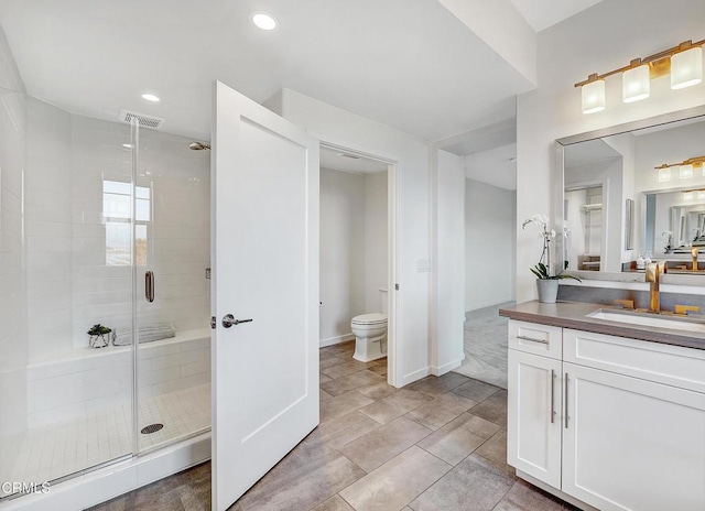 bathroom with vanity, toilet, visible vents, and a stall shower