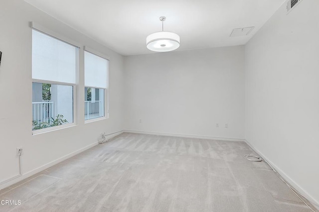 carpeted spare room with visible vents and baseboards