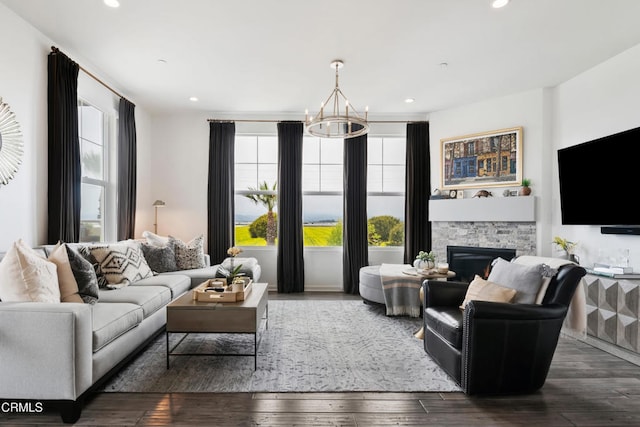 living room featuring recessed lighting, a notable chandelier, a stone fireplace, and hardwood / wood-style flooring