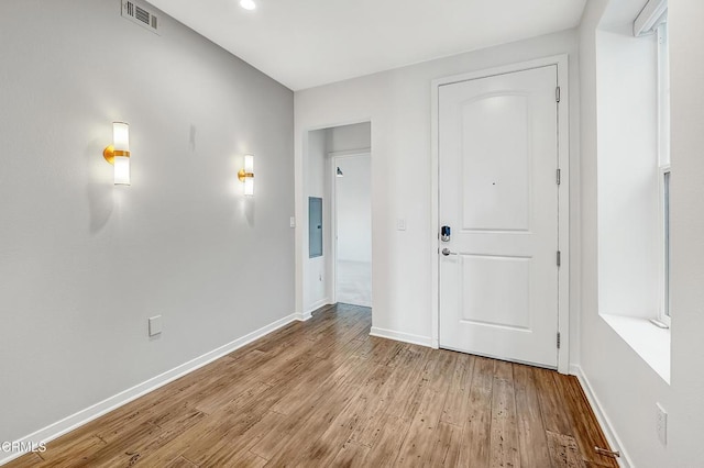 foyer with electric panel, visible vents, baseboards, and wood finished floors