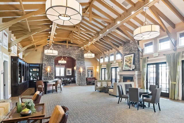 dining room featuring beam ceiling, high vaulted ceiling, a lit fireplace, and carpet floors