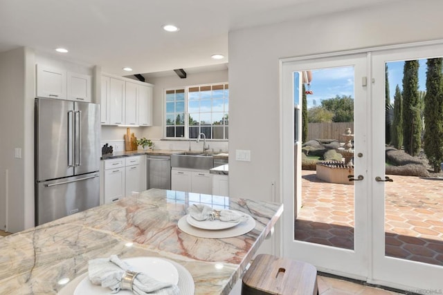 kitchen with light stone countertops, appliances with stainless steel finishes, sink, and white cabinets