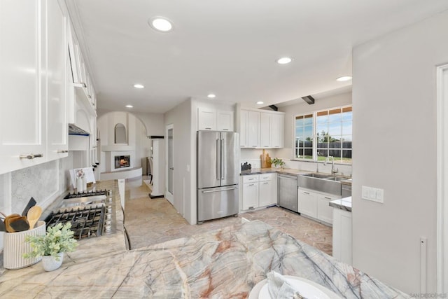 kitchen with backsplash, appliances with stainless steel finishes, sink, and white cabinets