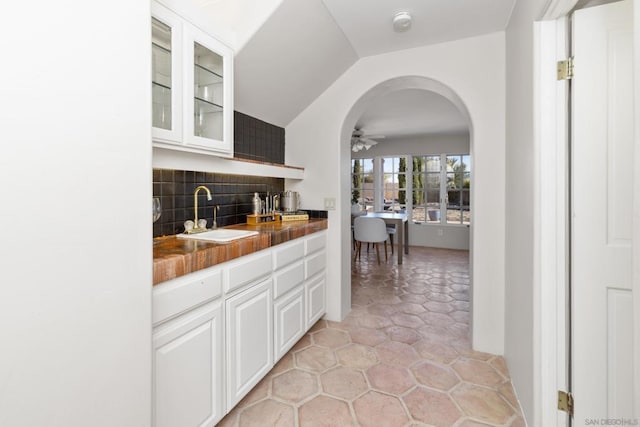 bar with sink, wooden counters, white cabinets, decorative backsplash, and vaulted ceiling