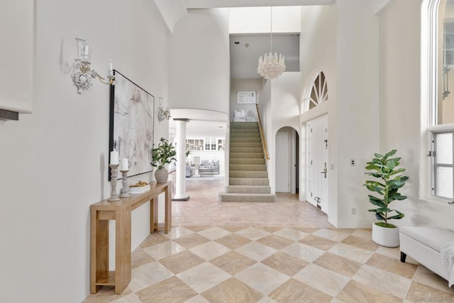 foyer featuring decorative columns, a towering ceiling, and an inviting chandelier