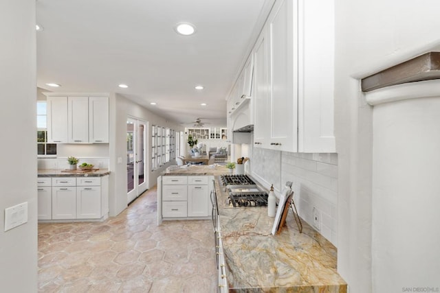 kitchen with light stone counters, white cabinets, and backsplash