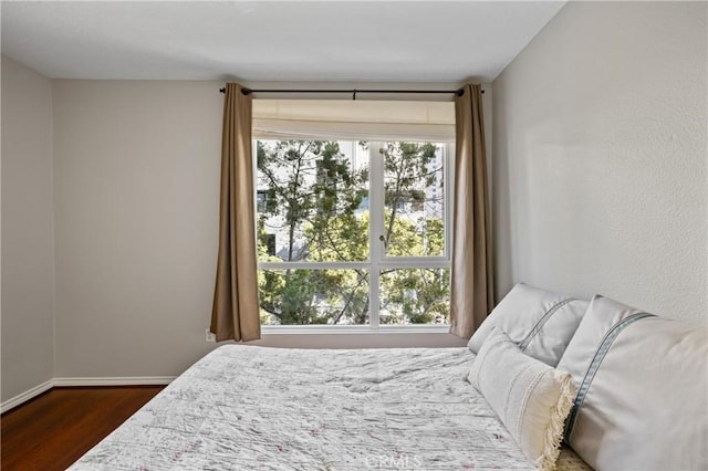 bedroom featuring multiple windows and dark hardwood / wood-style flooring