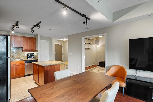 kitchen with a kitchen island, refrigerator, tasteful backsplash, stainless steel dishwasher, and light tile patterned floors