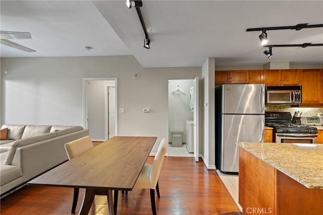 kitchen featuring tasteful backsplash, light wood-type flooring, ceiling fan, stainless steel appliances, and light stone countertops