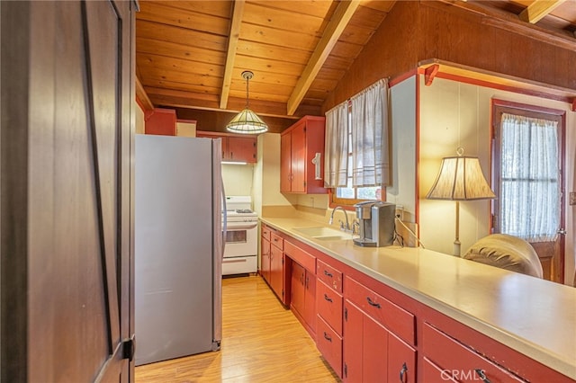 kitchen with sink, vaulted ceiling with beams, decorative light fixtures, stainless steel refrigerator, and white range with gas cooktop