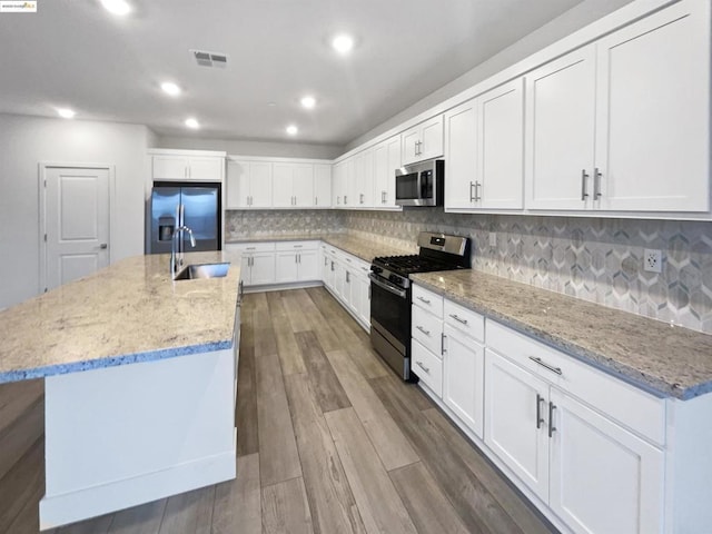 kitchen featuring white cabinetry, appliances with stainless steel finishes, and a center island with sink