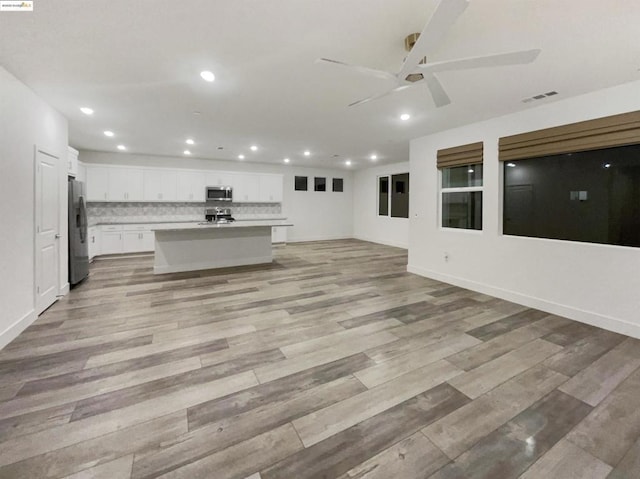 kitchen with decorative backsplash, appliances with stainless steel finishes, a center island with sink, and white cabinets