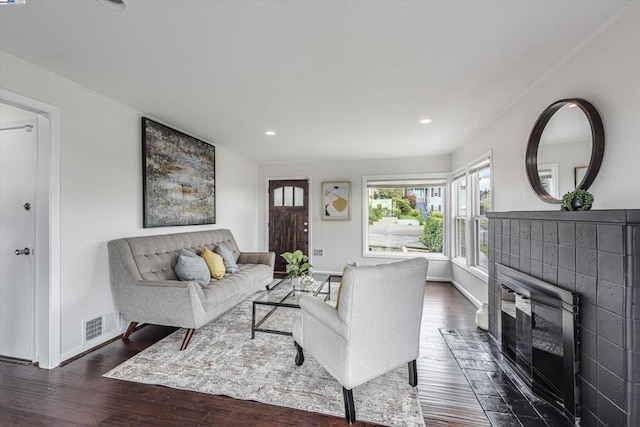 living room with dark wood-type flooring and a tile fireplace