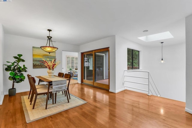 dining room featuring hardwood / wood-style flooring and a skylight