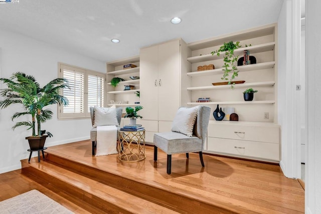 sitting room with light wood-type flooring and built in shelves