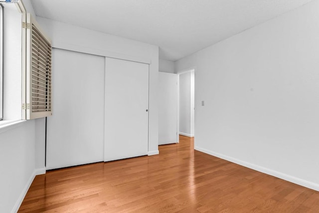 unfurnished bedroom with light hardwood / wood-style floors and a closet