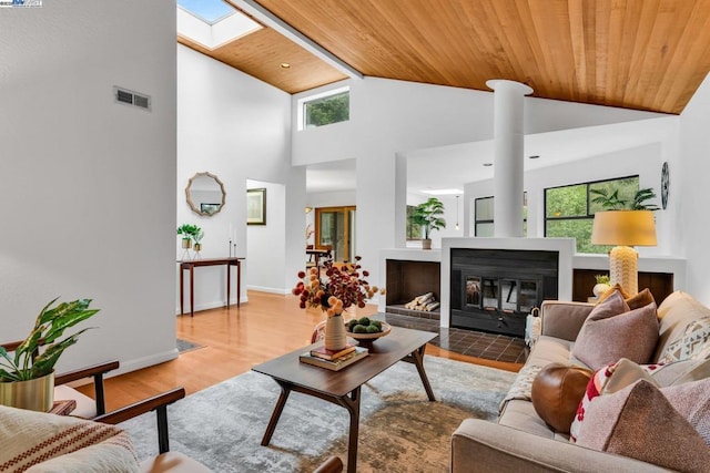 living room with high vaulted ceiling, wooden ceiling, light wood-type flooring, and a skylight