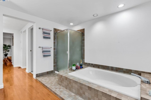 bathroom with independent shower and bath and hardwood / wood-style floors