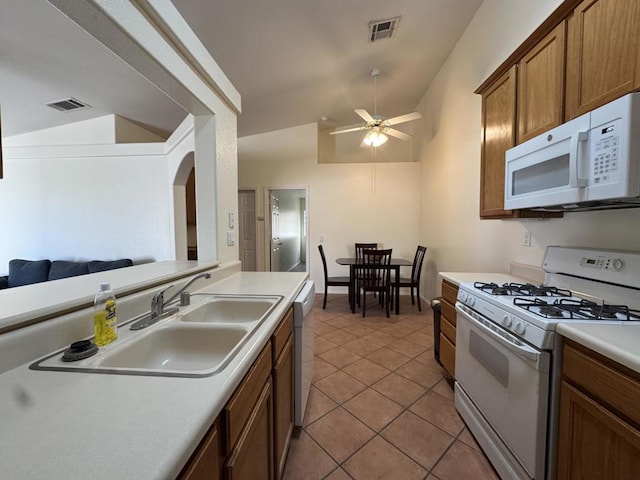 kitchen featuring sink, white appliances, vaulted ceiling, light tile patterned floors, and ceiling fan