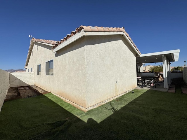 view of property exterior with a patio area and a lawn