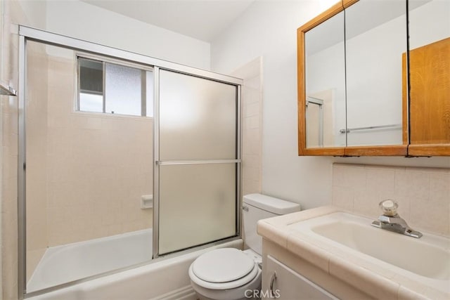 full bathroom featuring vanity, backsplash, shower / bath combination with glass door, and toilet