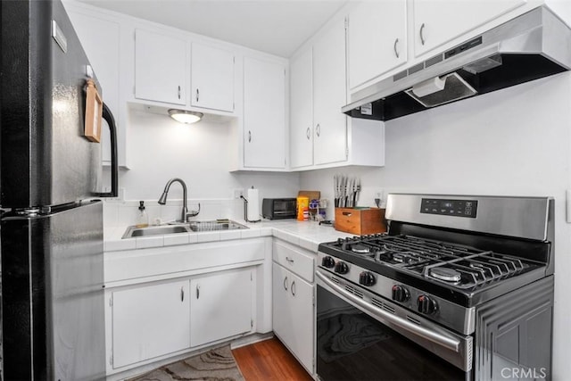 kitchen with white cabinetry, sink, black refrigerator, and stainless steel range with gas stovetop