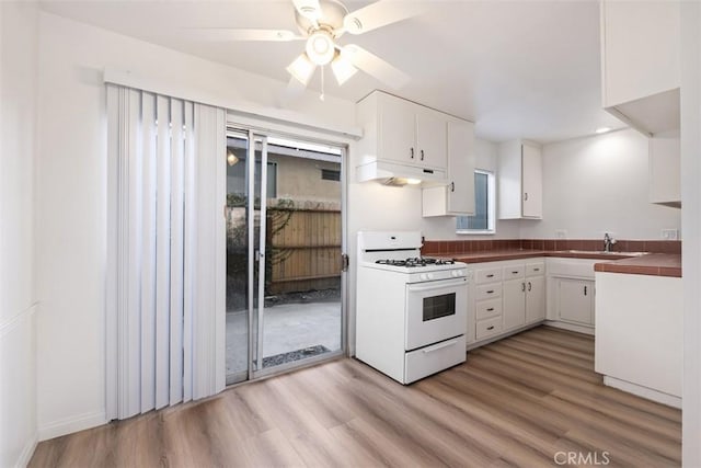 kitchen with sink, white cabinets, white range with gas stovetop, ceiling fan, and light hardwood / wood-style flooring