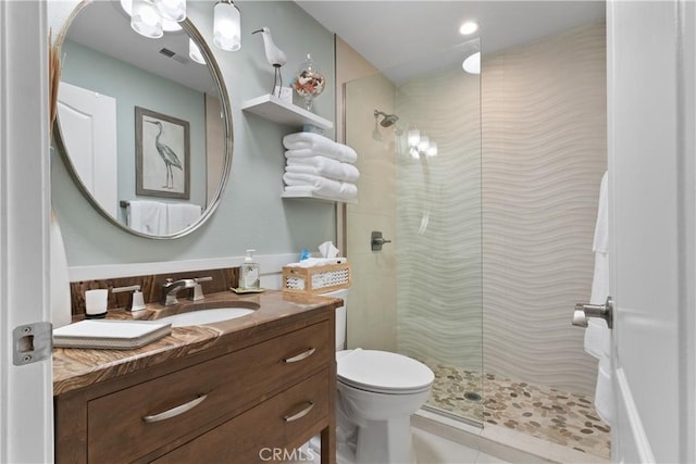 bathroom with vanity, tiled shower, and toilet