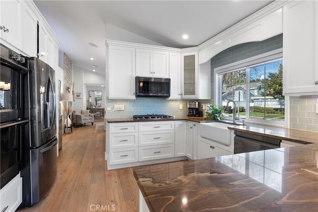 kitchen with sink, white cabinets, decorative backsplash, light hardwood / wood-style floors, and black appliances