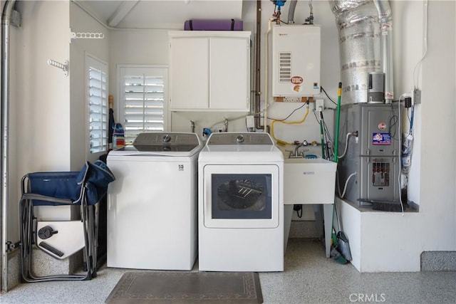 clothes washing area with water heater, washing machine and dryer, sink, and cabinets