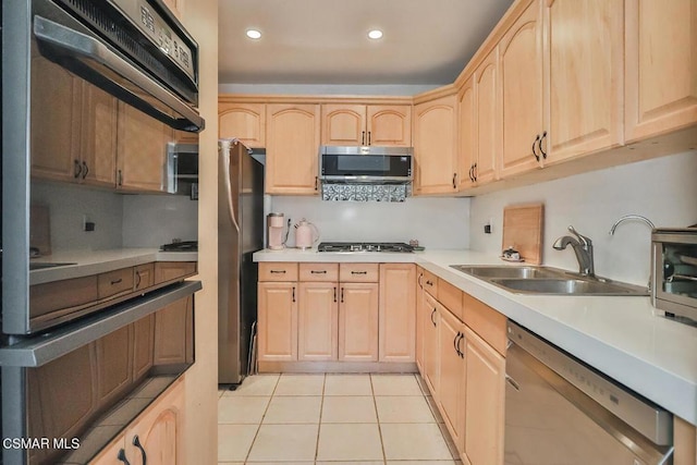 kitchen featuring light tile patterned flooring, appliances with stainless steel finishes, light brown cabinetry, sink, and exhaust hood