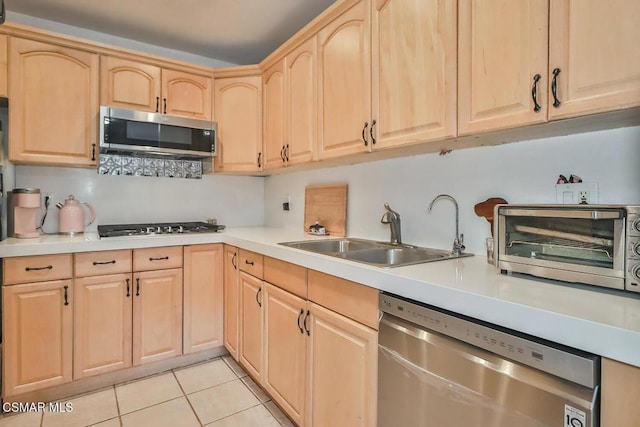 kitchen featuring stainless steel appliances, light brown cabinetry, sink, and light tile patterned floors