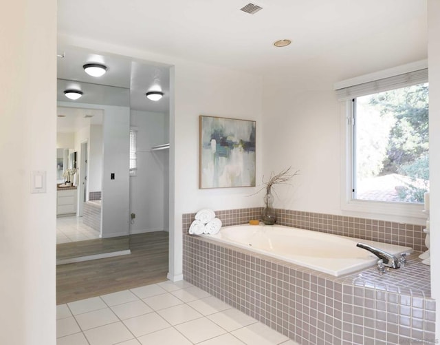 bathroom with tile patterned floors and tiled bath