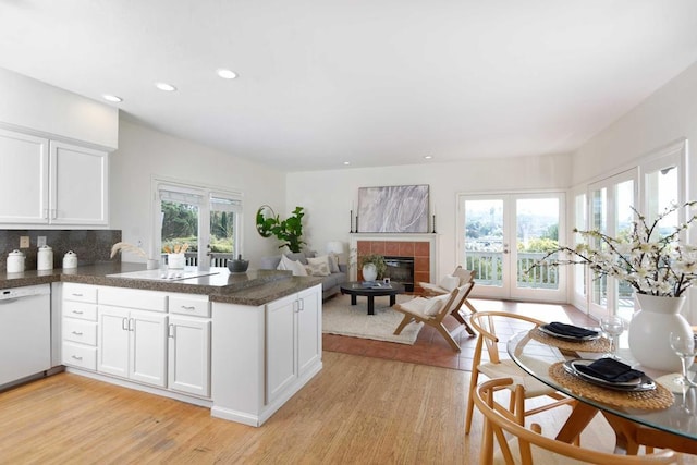 kitchen with dishwasher, kitchen peninsula, light hardwood / wood-style floors, decorative backsplash, and white cabinets