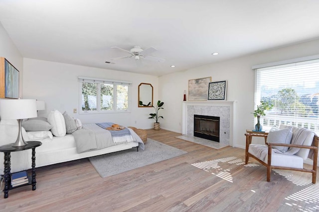 bedroom with ceiling fan, a fireplace, and light wood-type flooring